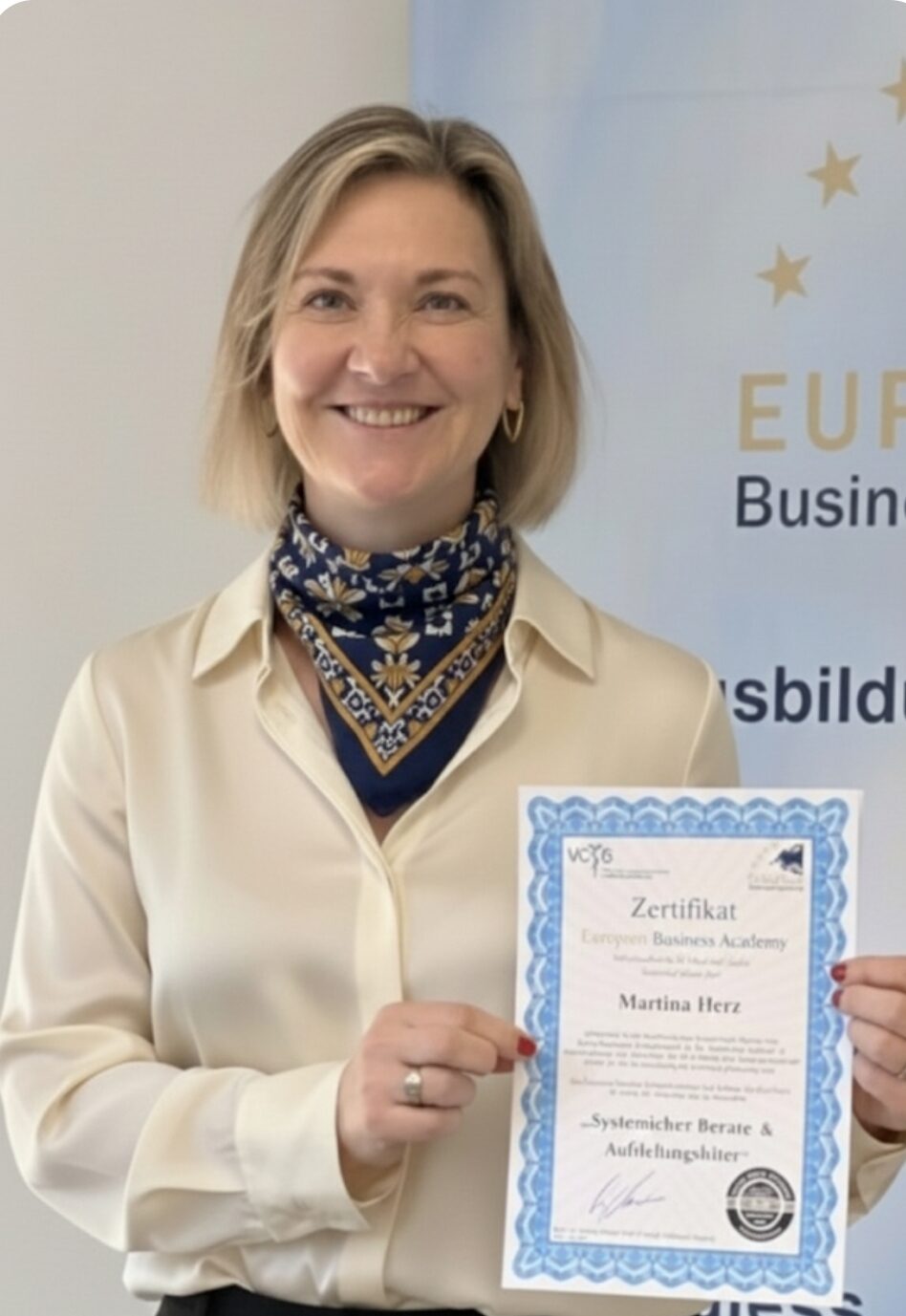 Martina Herz hält ihre Zertifizierung "Systemischer Berater und Aufstellungsleiter" in den Händen